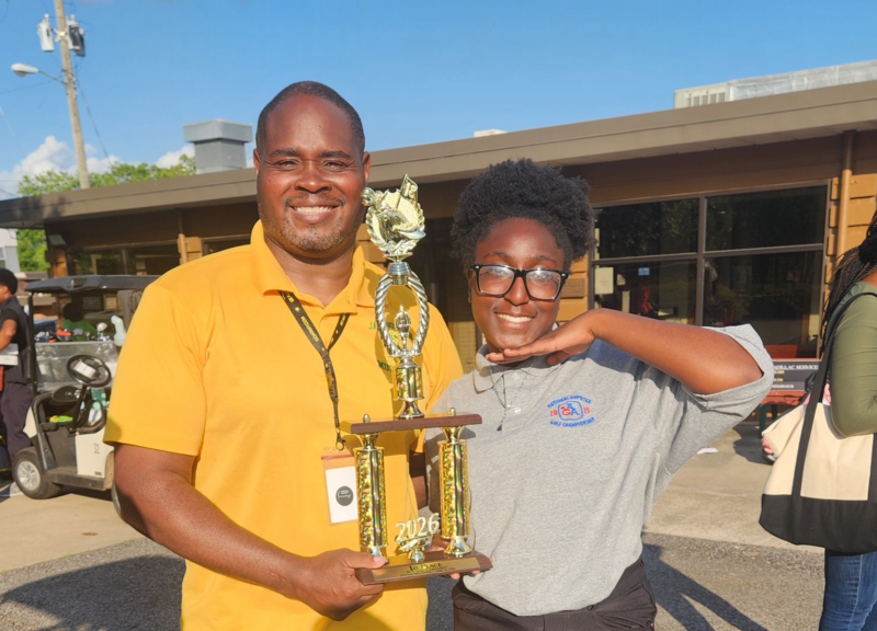 Coach Robert Coker and Hayden Gray hold the 2026 BCS Golf Championship Trophy