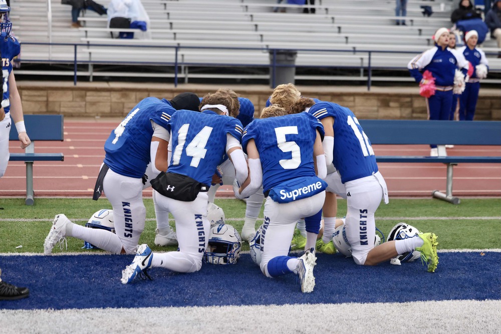 Football players kneeling in prayer