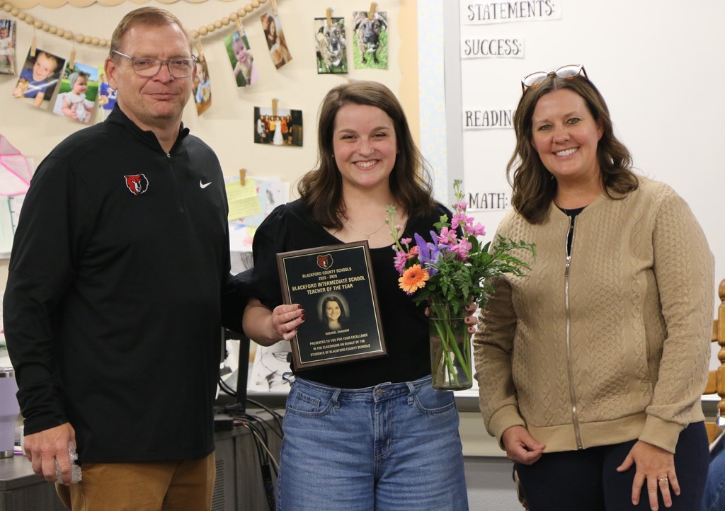 Rachael Shadiow holds the flowers and plaque presented to her as the Teacher of the Year at Blackford Intermediate School. She is joined by Superintendent Chad Yencer and Assistant Superintendent Lesley Moulton