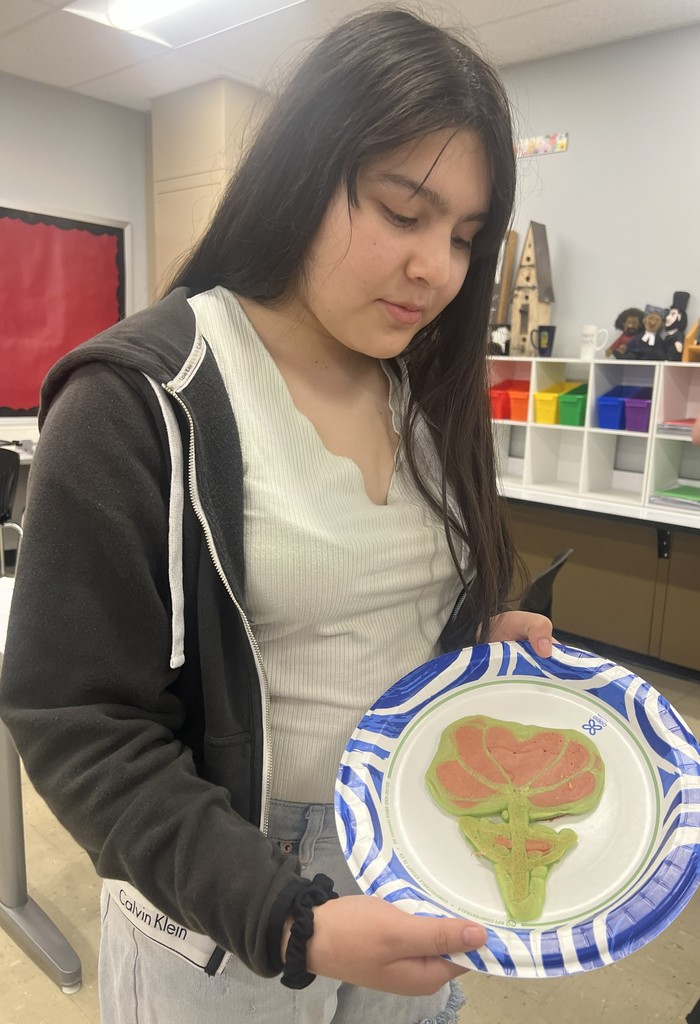 A BJSHS 7th or 8th grade girl shows her pancake art in the shape of a flower