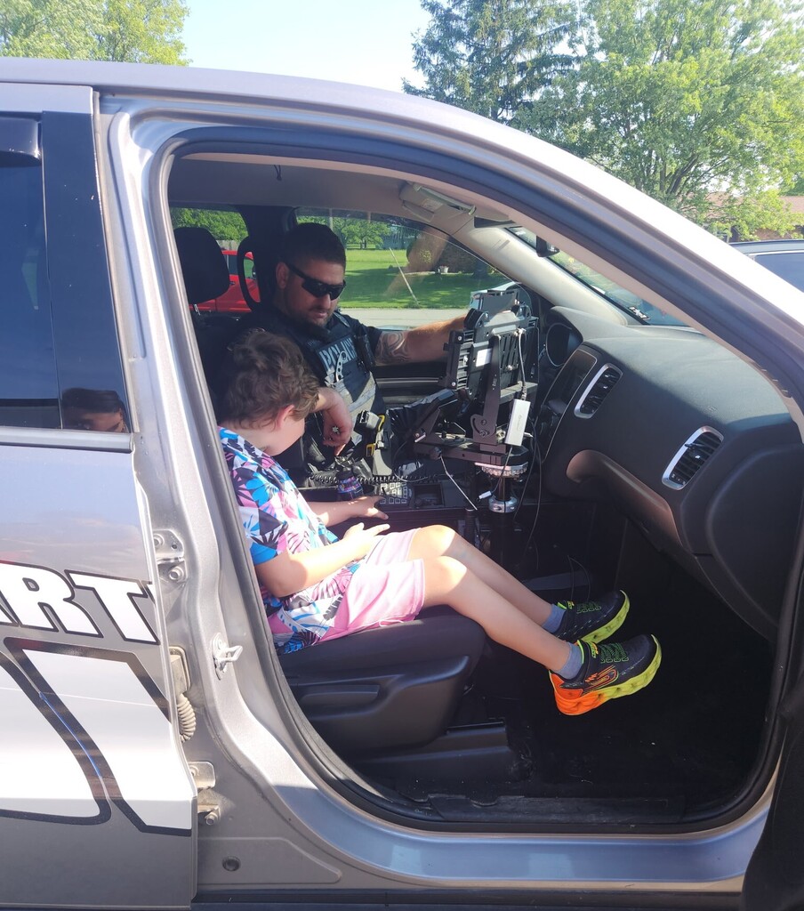 A BPS boy learns about the interior of a police car with a policeman