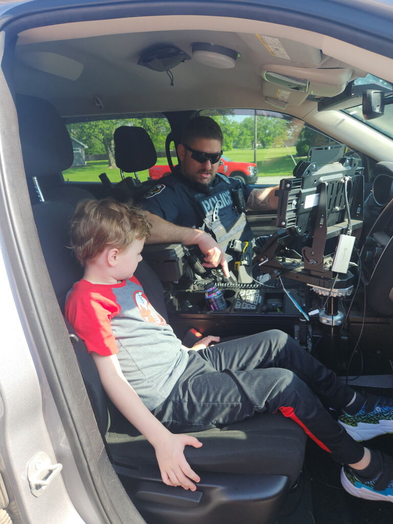 A BPS boy learns about the interior of a police car with a policeman