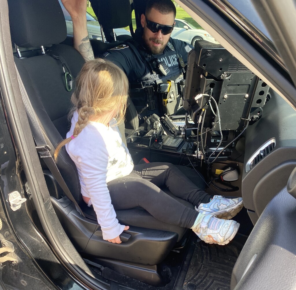 A BPS girl learns about the interior of a police car with a policeman