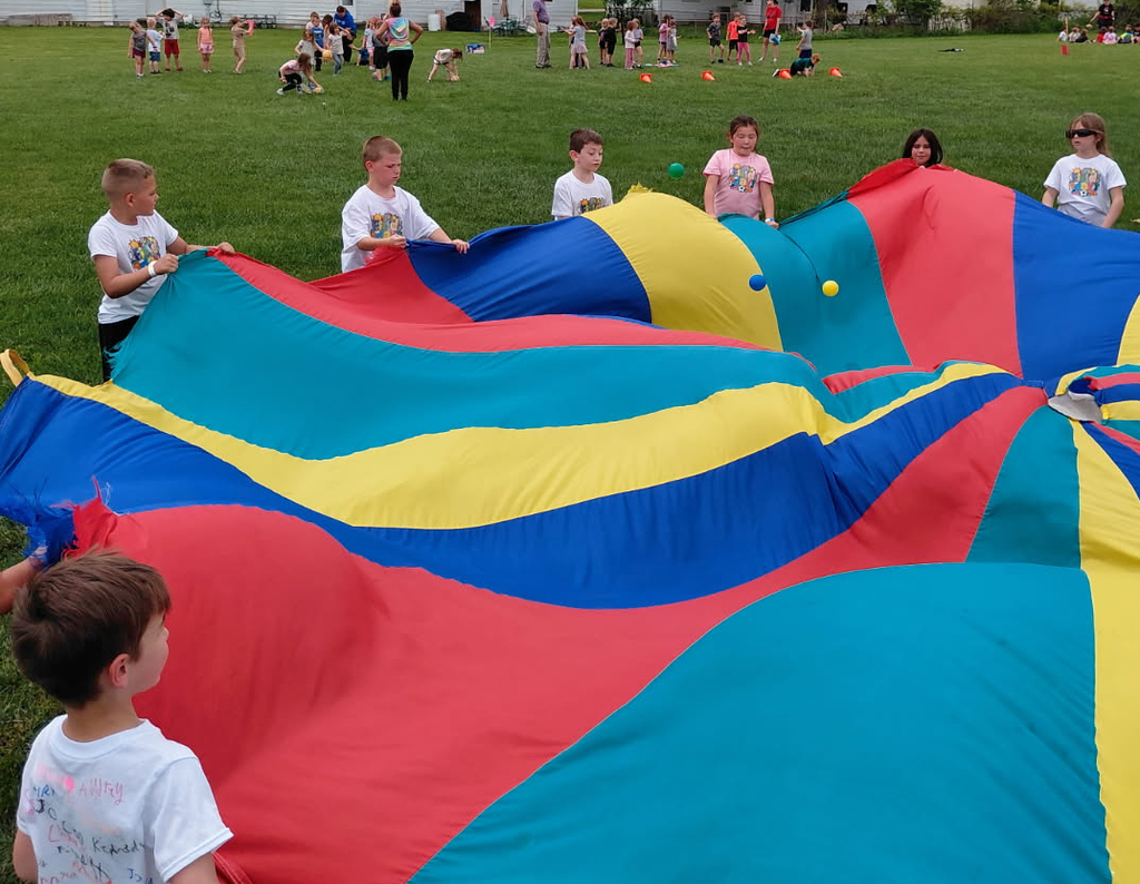 BPS students play a ball game with a colorful parachute during the BPS End of School Field Day