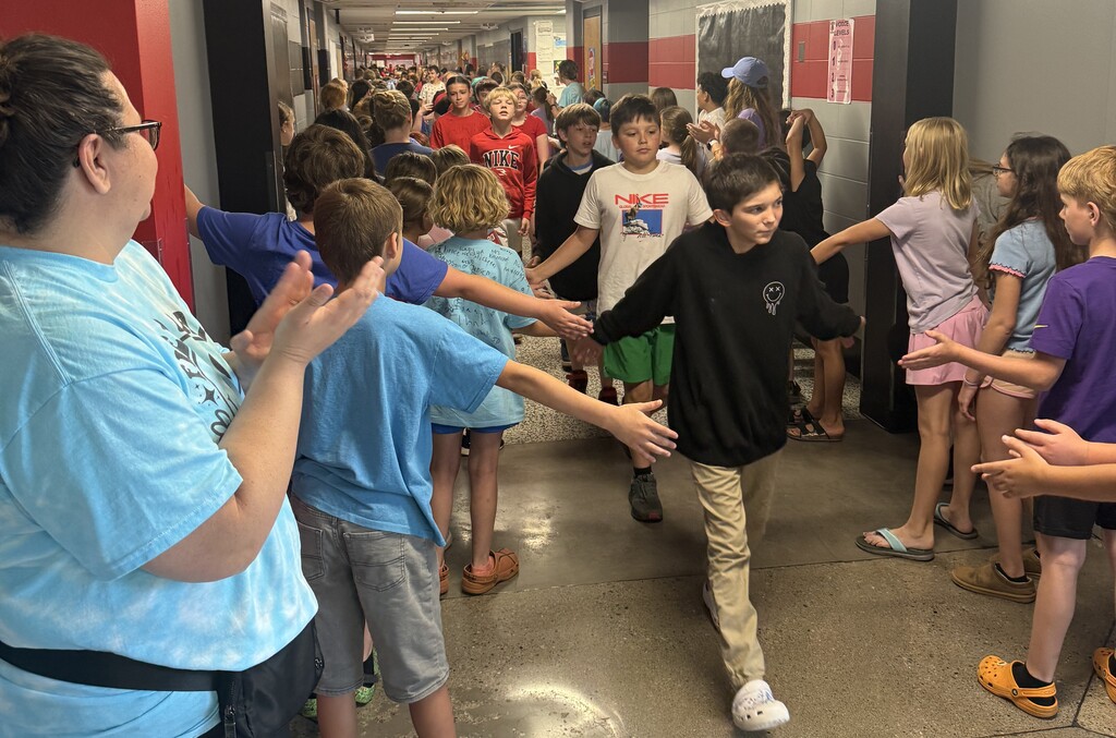 A 6th grade boy is being congratulated by the 4th and 5th grade at the BIS for completing 6th grade