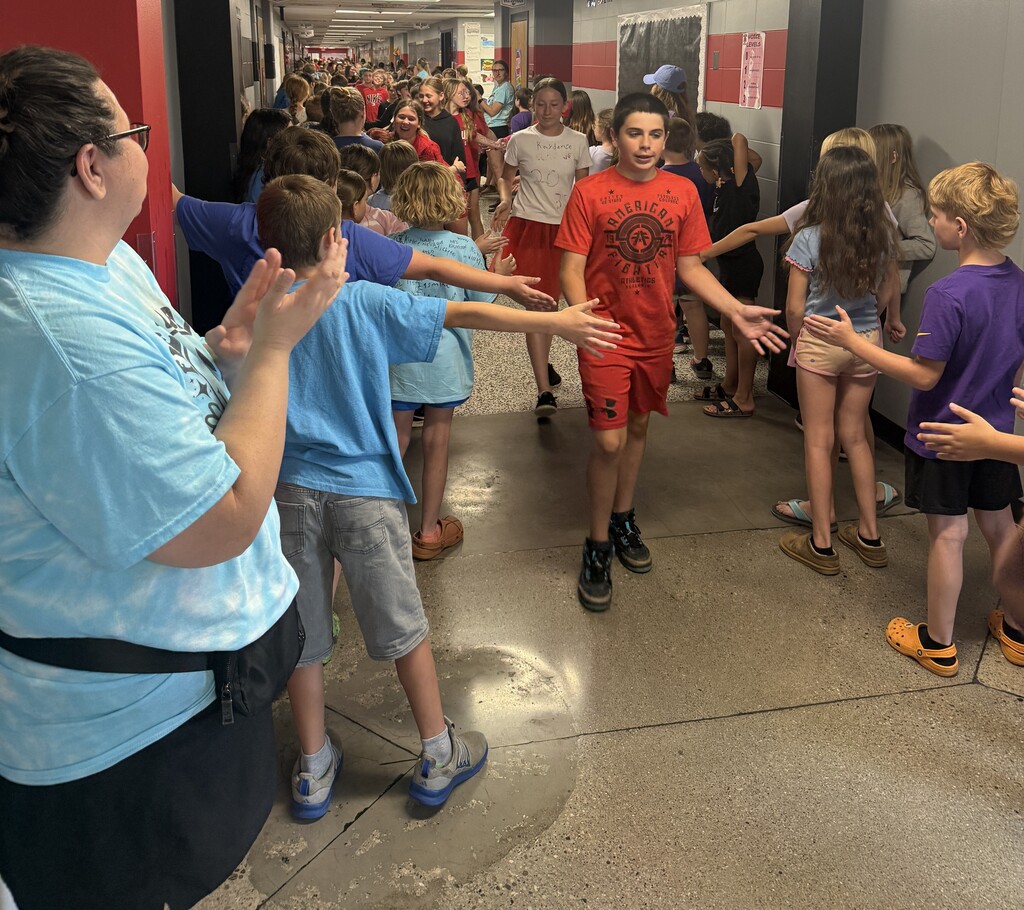 A 6th grade boy is being congratulated by the 4th and 5th grade at the BIS for completing 6th grade