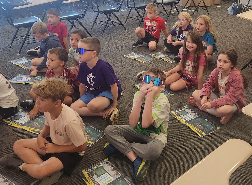 Students sit on the floor during a Camp Invention lesson.