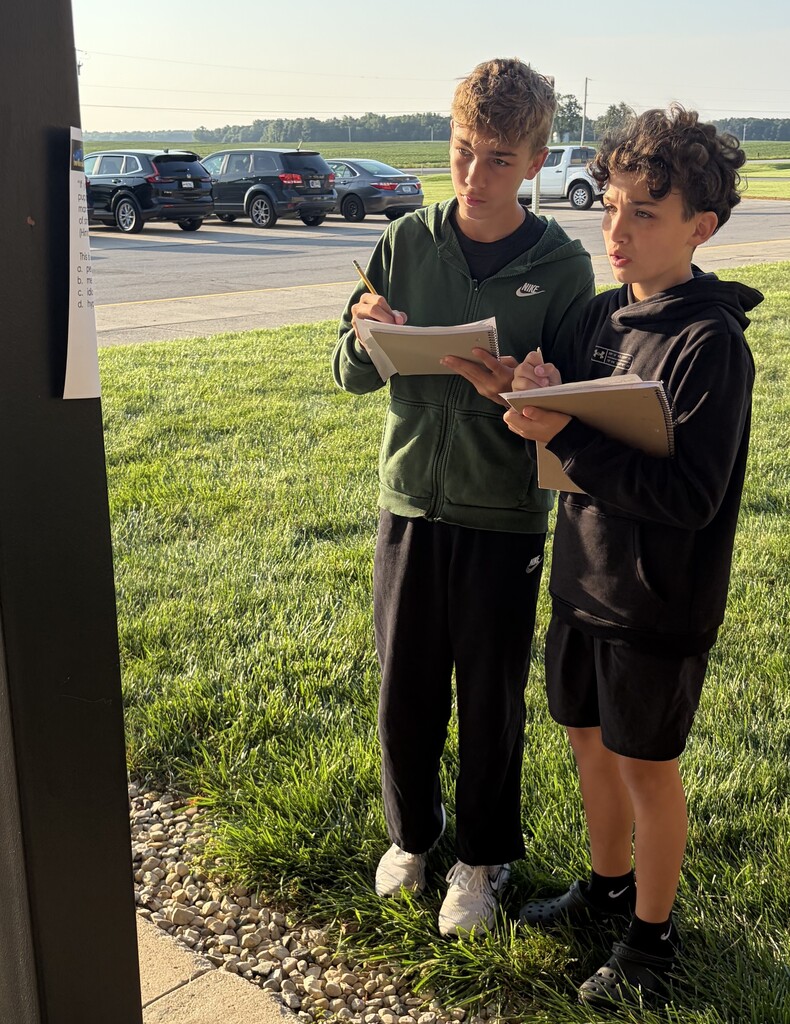 Two 7th grade boys work on a scavenger hunt using passages from The Outsiders