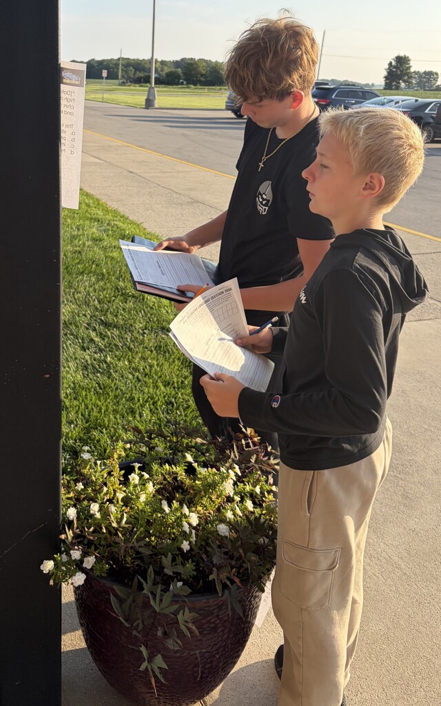 Two 7th grade boys work on a scavenger hunt using passages from The Outsiders