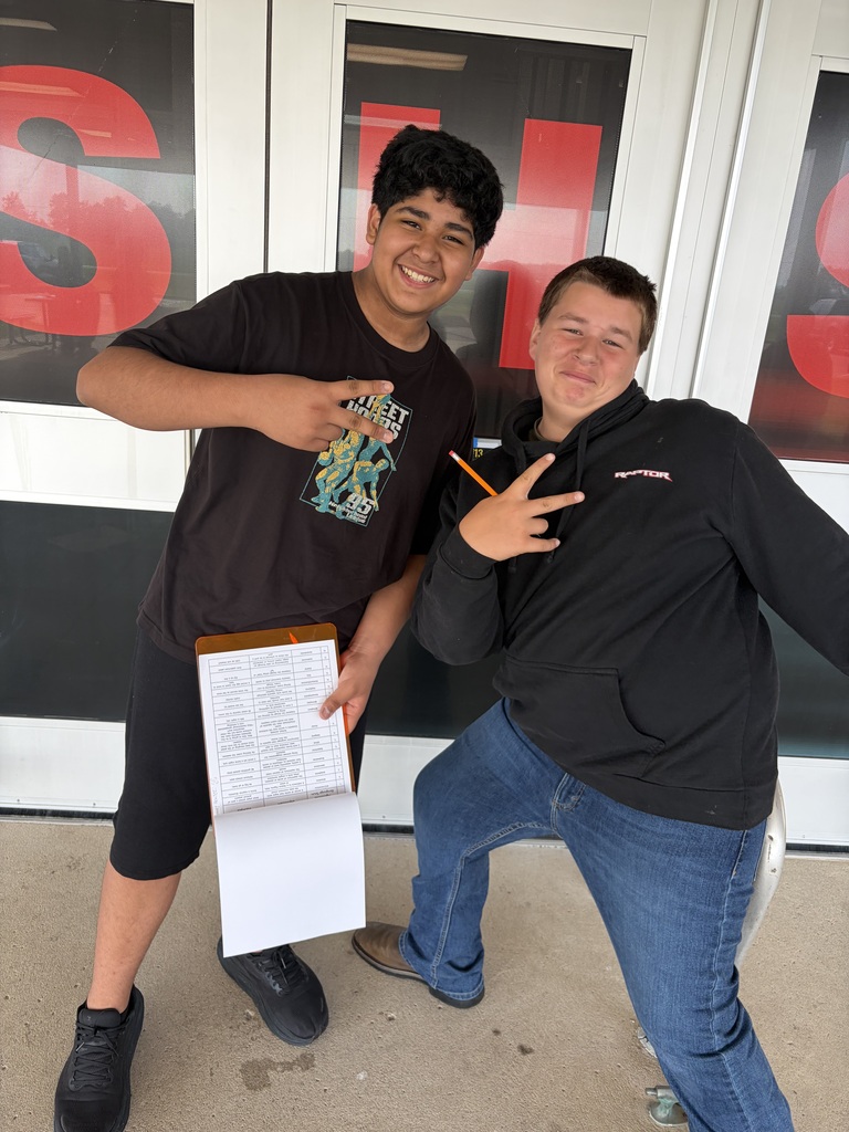Two 7th grade boys pose for a photos as they work on a scavenger hunt using passages from The Outsiders