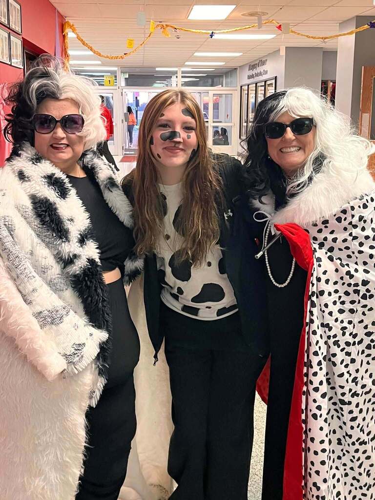 Two staff members dress as Cruella Deville and one dresses as a dalmation dog