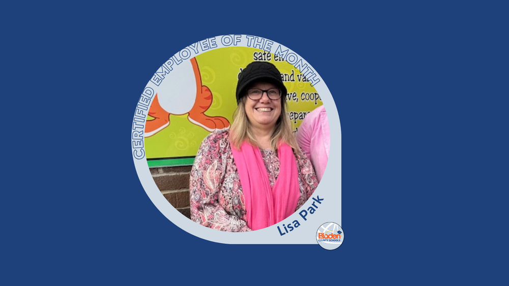Graphic announcing Certified Employee of the Month featuring Lisa Park, smiling while standing in front of a colorful school display, wearing glasses, a patterned blouse, and a pink scarf, with Bladen County Schools logo.