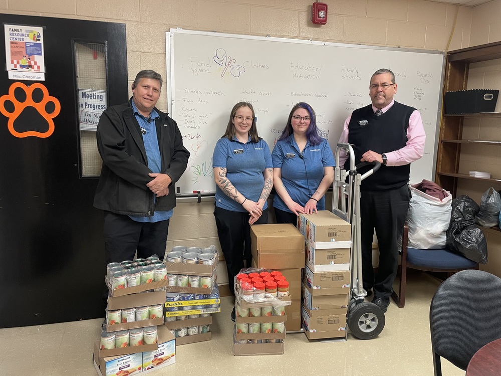Four adults from Food Lion stand with food donations.
