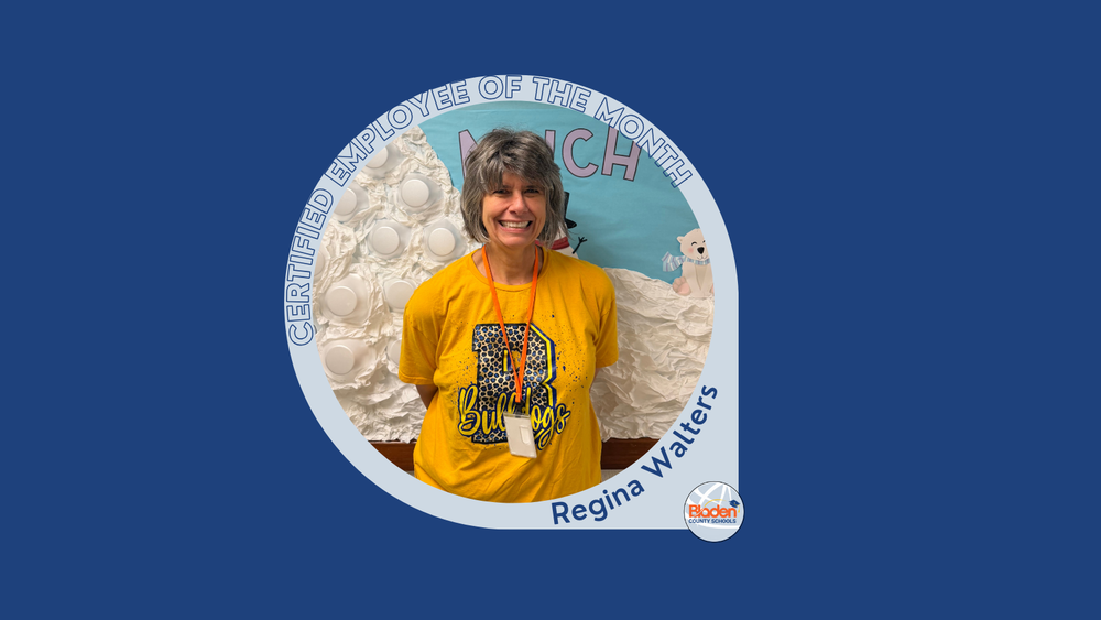  Portrait of Regina Walters, Certified Employee of the Month, smiling in a yellow Bulldogs T-shirt and lanyard, standing in front of a winter-themed classroom display, shown within a Bladen County Schools recognition graphic.