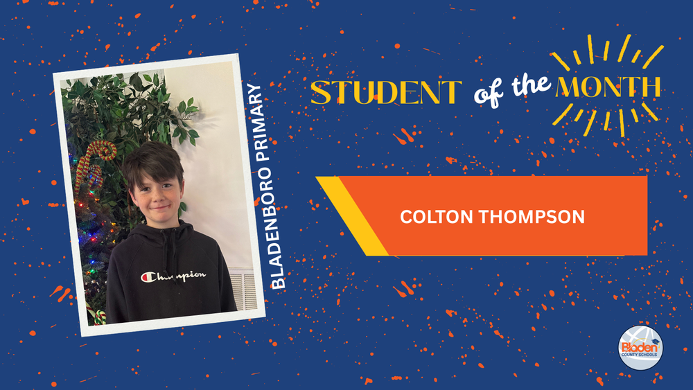 Student of the Month graphic featuring Colton Thompson from Bladenboro Primary, smiling while standing in front of a decorated Christmas tree and greenery, wearing a black hoodie, with bold blue and orange design elements and Bladen County Schools logo.