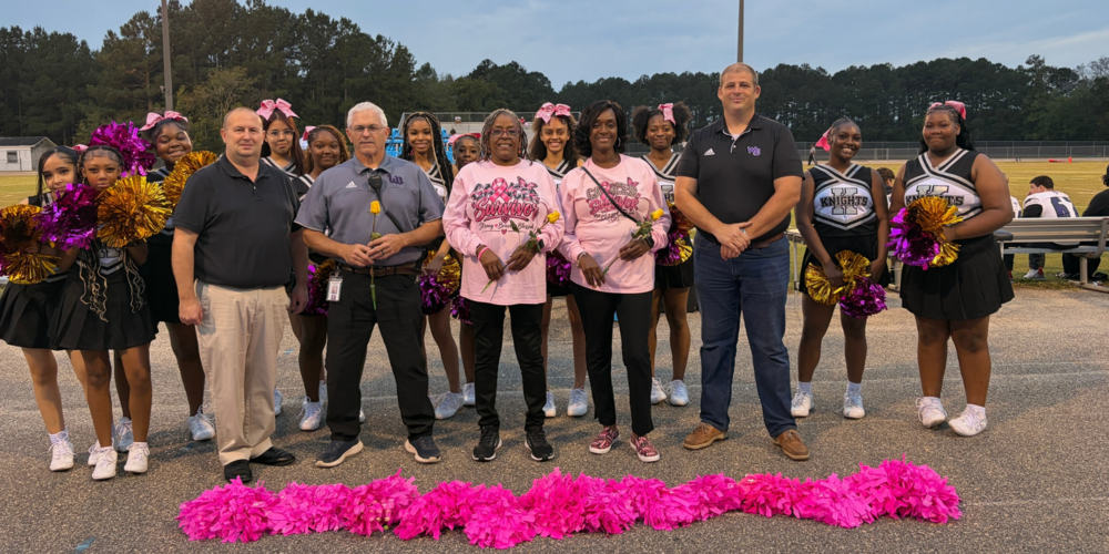 West Bladen High School cheerleaders, Superintendent Dr. Jason Atkinson, and Principal Chris Orrock, stand together with 4 cancer survivors. 