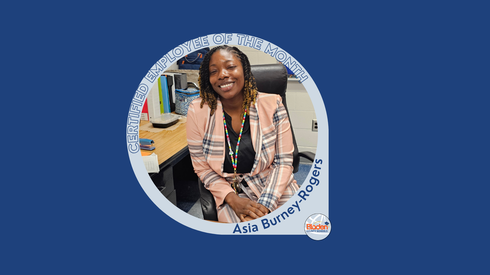 Graphic announcing Certified Employee of the Month featuring Asia Burney-Rogers, smiling while seated at a desk in an office setting, wearing a patterned blazer and colorful lanyard, with Bladen County Schools logo.