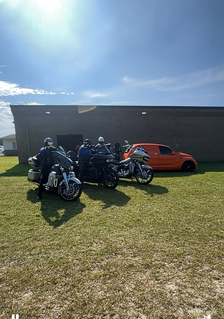 three motorcycles and an orange car in front of building