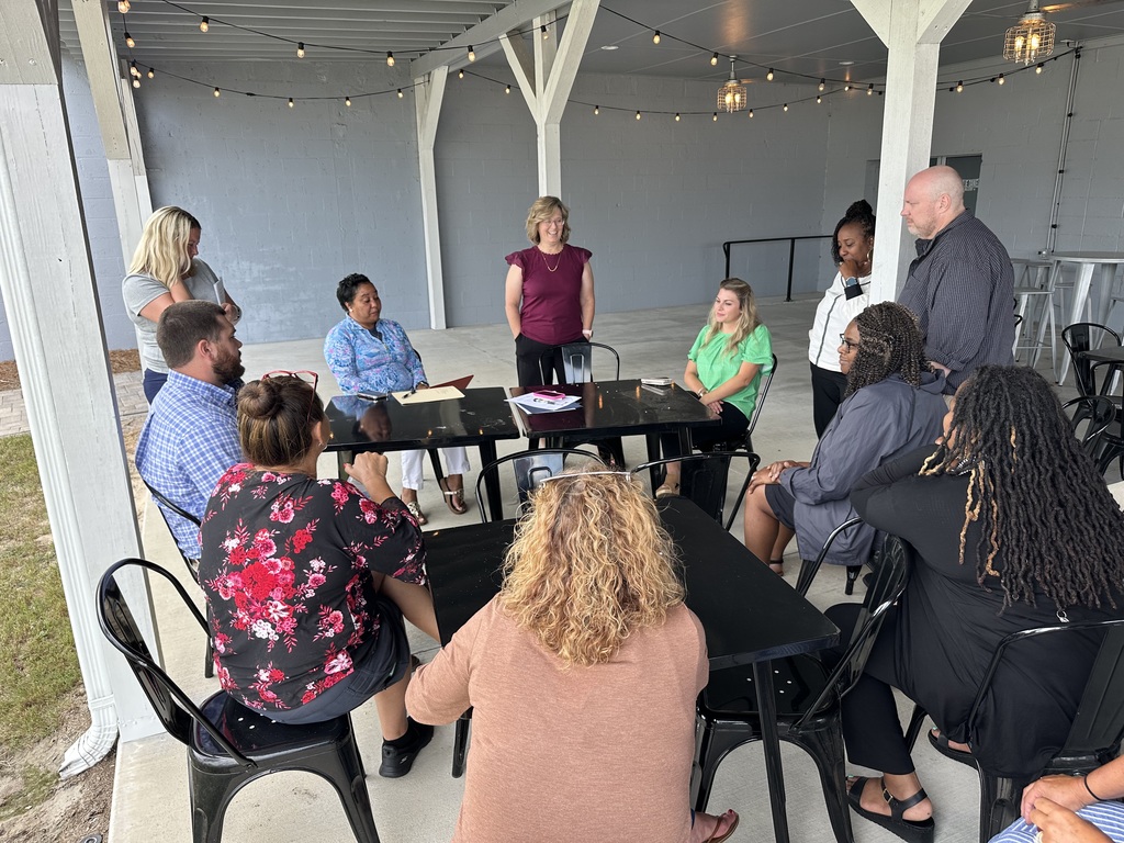 Team of school staff participating in a breakout session under a covered pavilion.