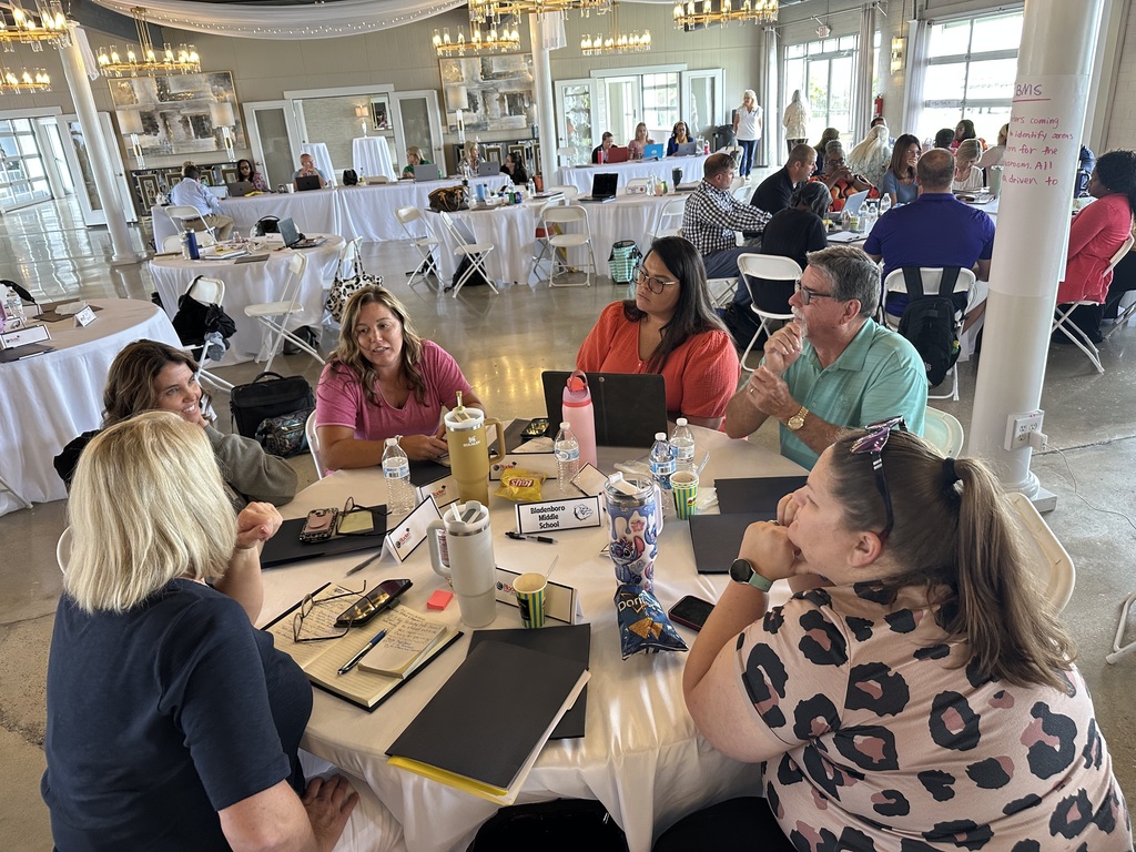 Bladenboro Middle School team collaborating at a table with laptops and materials.