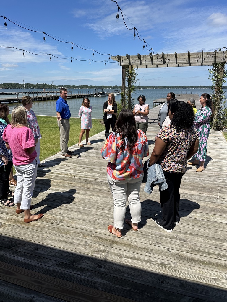 Group of educators gathered outside under a pergola near the waterfront during a leadership retreat.