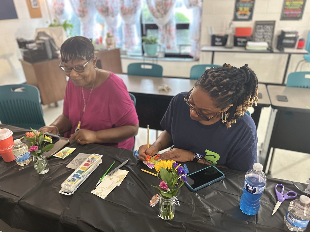 Two women focused on watercolor painting at a decorated table.