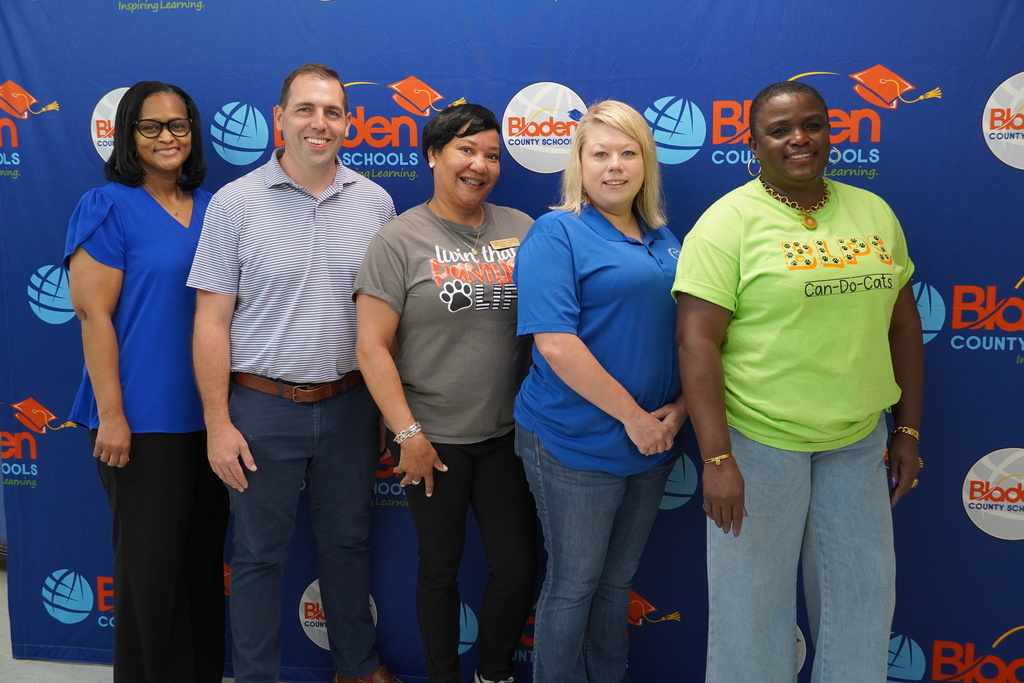 Group of five Bladen County Schools staff smiling in front of district backdrop