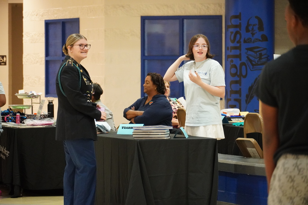 Students and staff chat at information tables during freshman orientation.