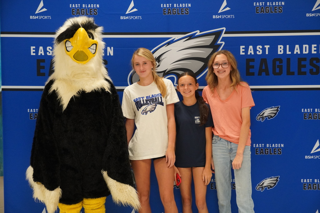 East Bladen mascot poses with three students in front of an Eagles backdrop.
