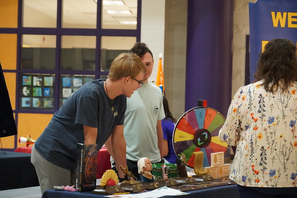 Students engage at a colorful activity booth with a spinning prize wheel.