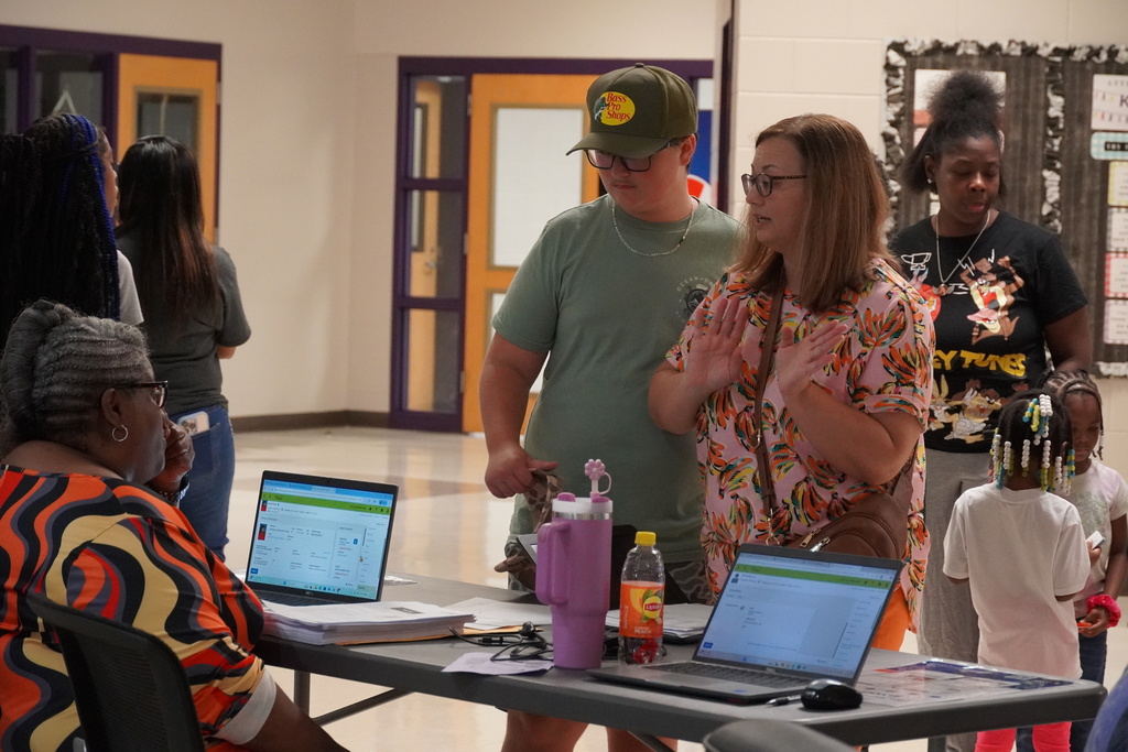 Parent and student receive help at a registration table with laptops open.