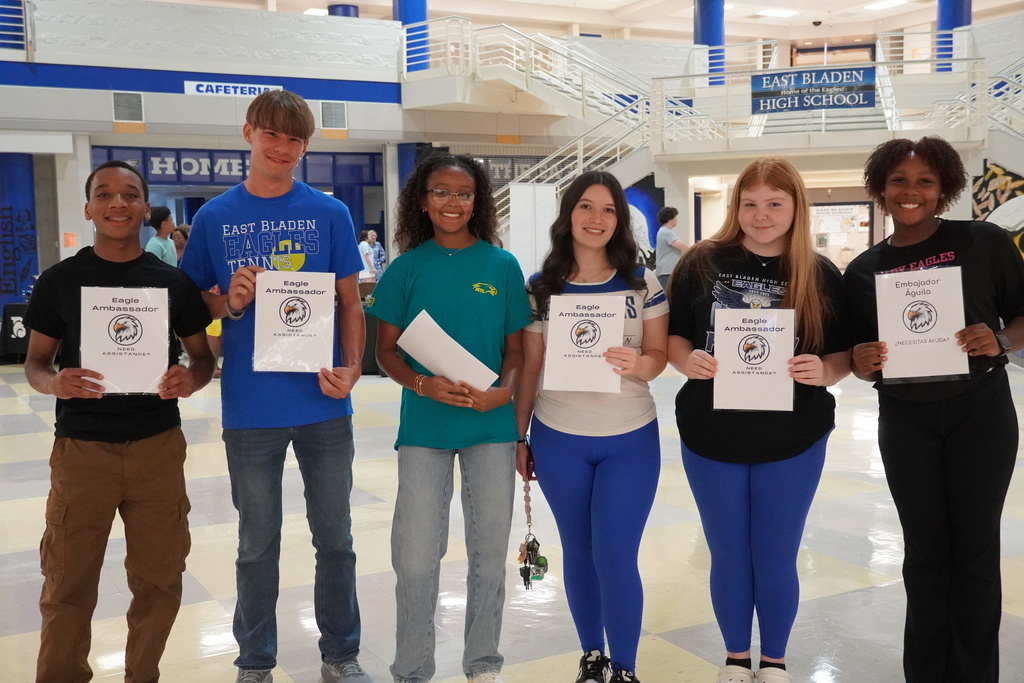 Six East Bladen Eagle Ambassadors hold welcome signs inside the school lobby.
