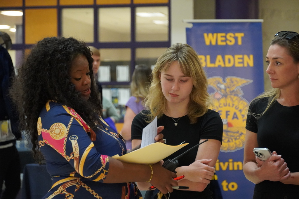 Teacher reviews a schedule with a student and parent during Open House at West Bladen.