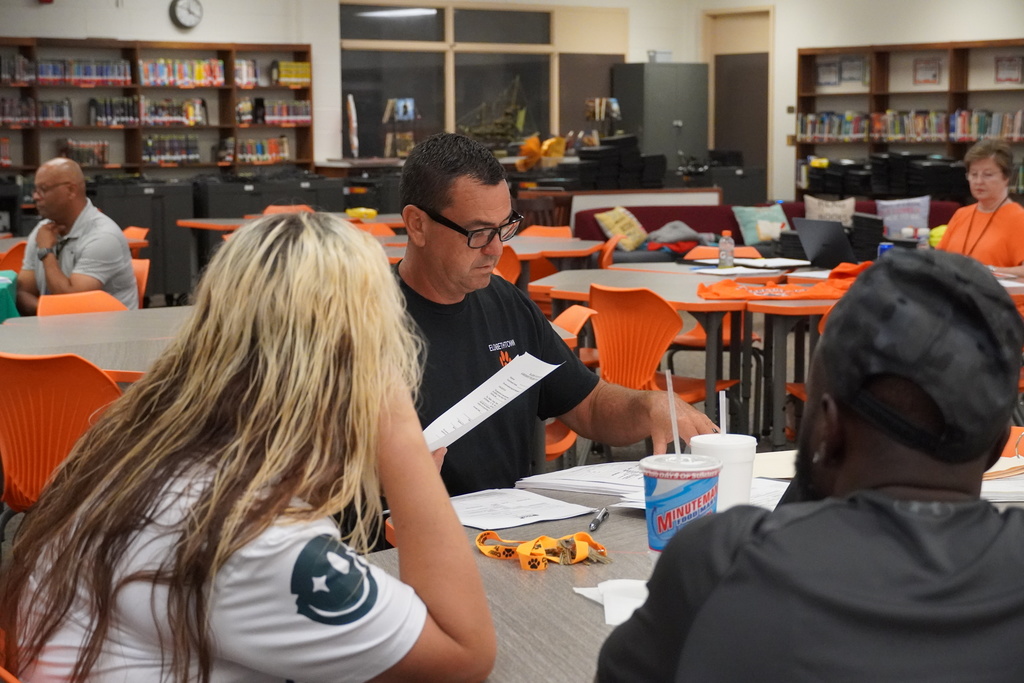 Parent and staff member review papers during Open House in a school media center.