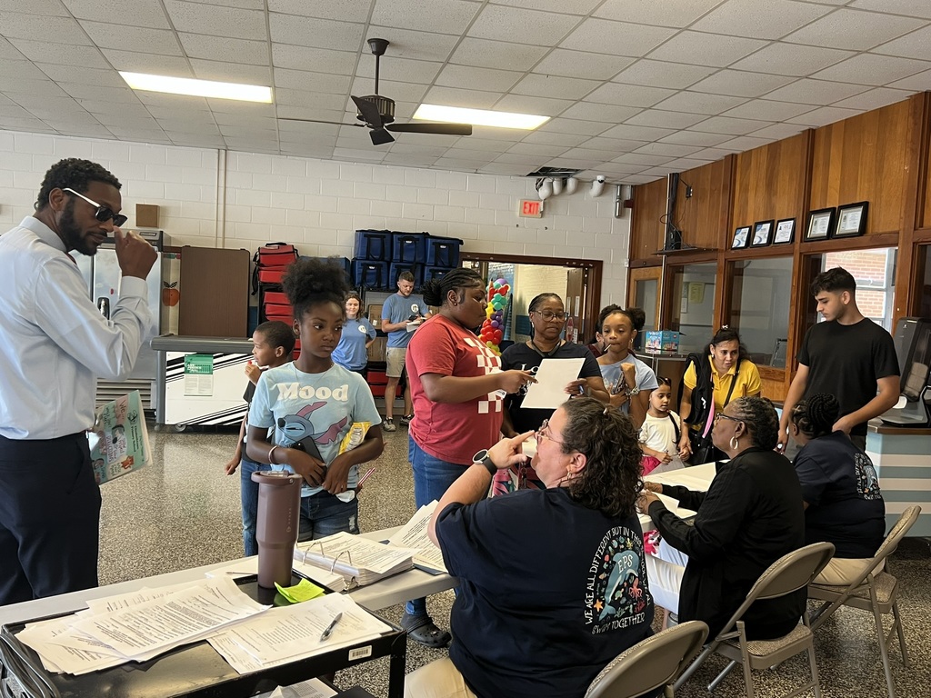 Teacher sharing information with parents at a classroom table.