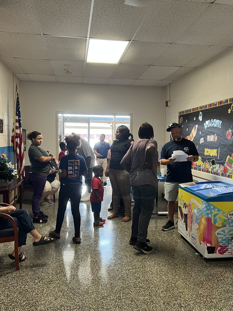 Families and staff talking in the hallway near a welcome back bulletin board.