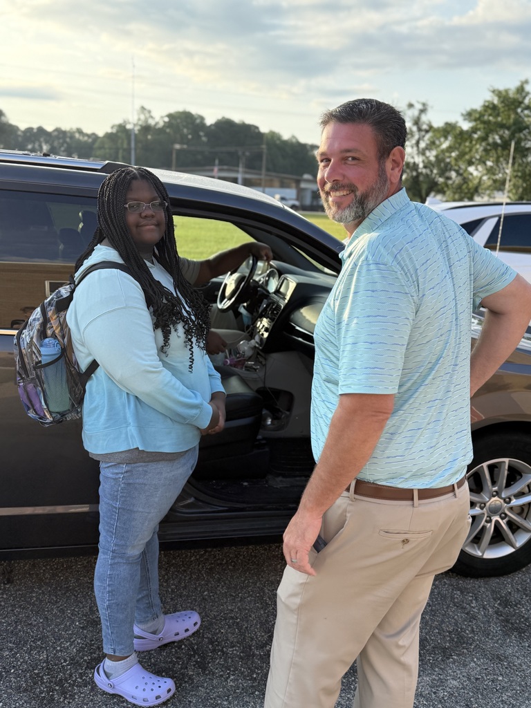 Principal greets student arriving at school drop-off with a smile.