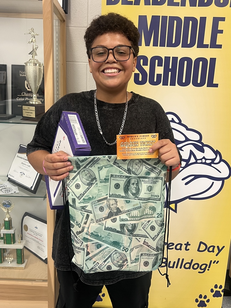 Golden ticket winner at middle school- boy wearing a black shirt and black shorts holding a golden ticket and prize