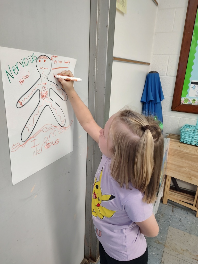 A student in a Pikachu shirt works on a figure labeled “Nervous,” drawing squiggly lines and writing about body reactions like a fast heartbeat.