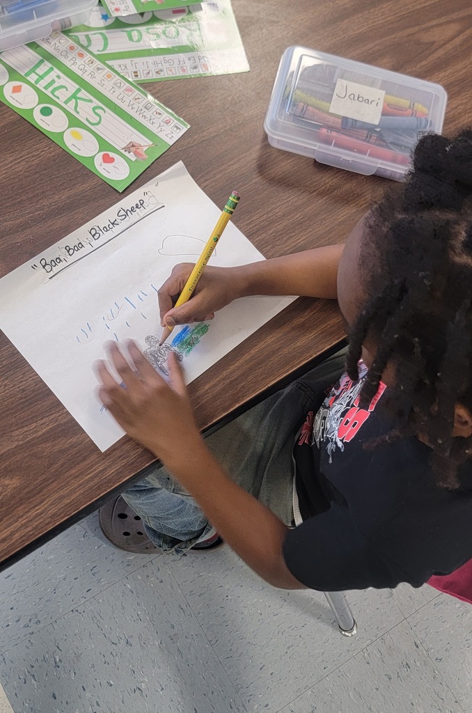 Student works on a “Baa Baa Black Sheep” drawing with pencil and crayon.