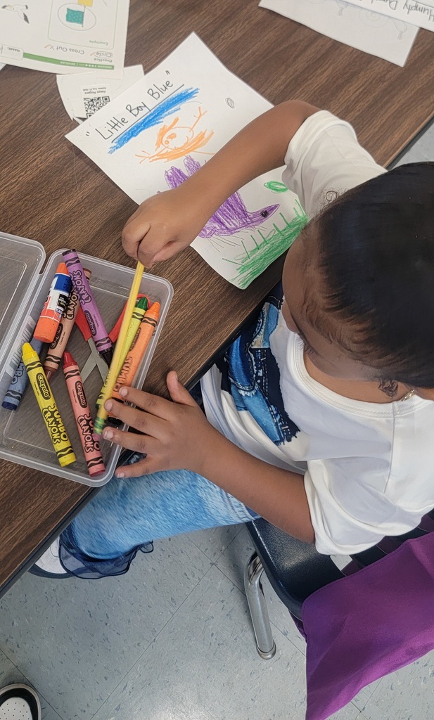 A student colors a bright picture labeled “Little Boy Blue” with purple, orange, and blue crayons.