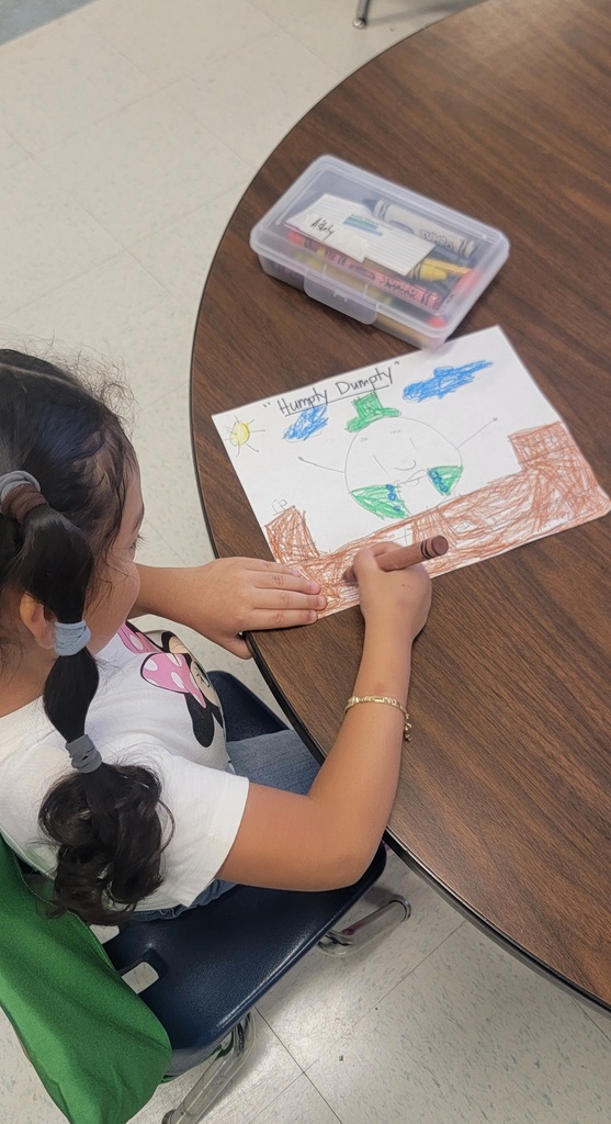 A student with pigtails colors a picture of “Humpty Dumpty,” showing the character sitting on a wall with blue sky above.