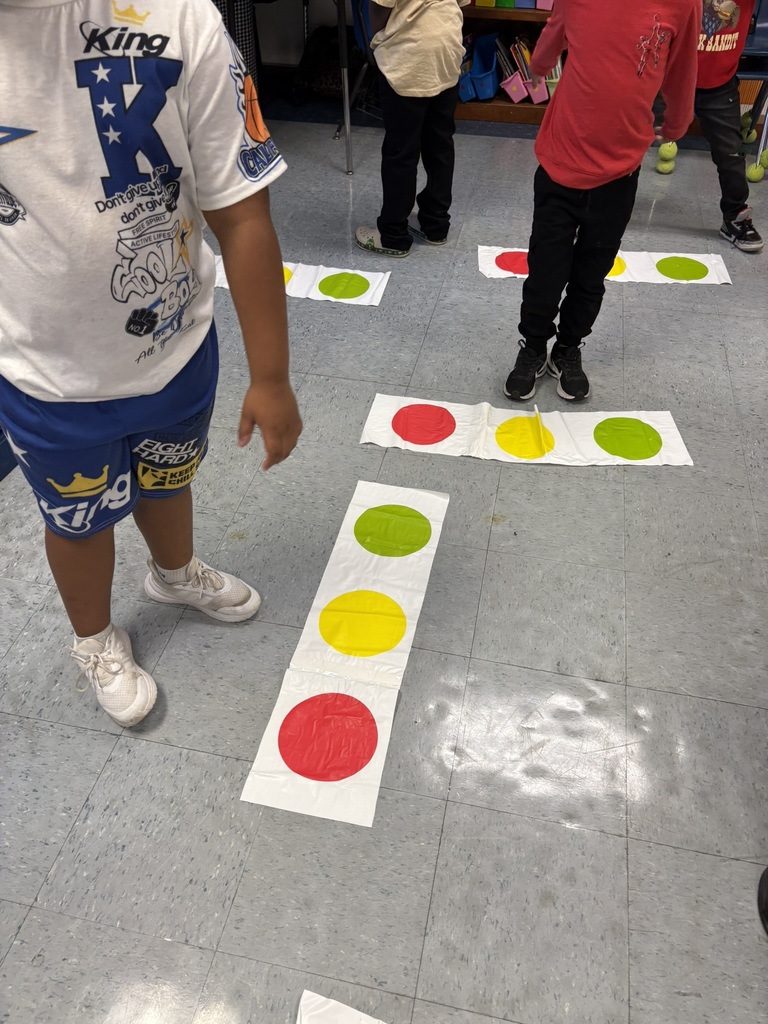 Close-up of children stepping on red, yellow, and green dot mats on the classroom floor.