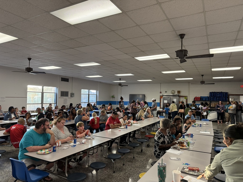 Cafeteria filled with families sitting at tables enjoying Bingo night.