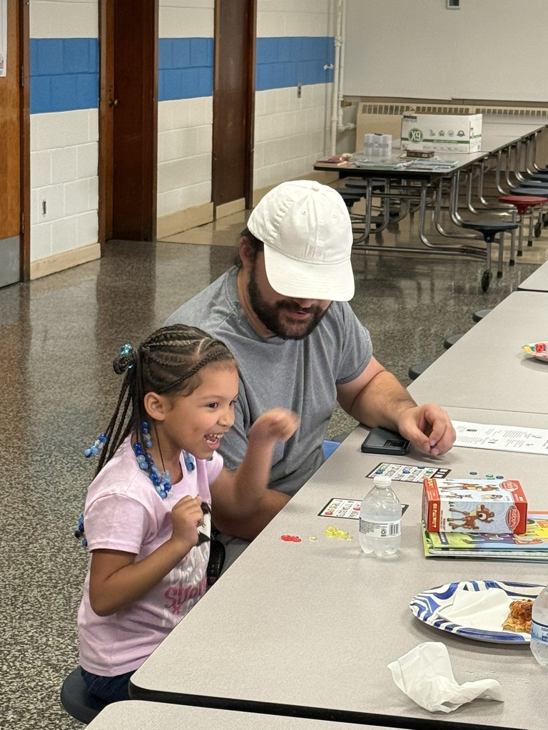 Dad and daughter sit together playing Bingo; the girl smiles excitedly.