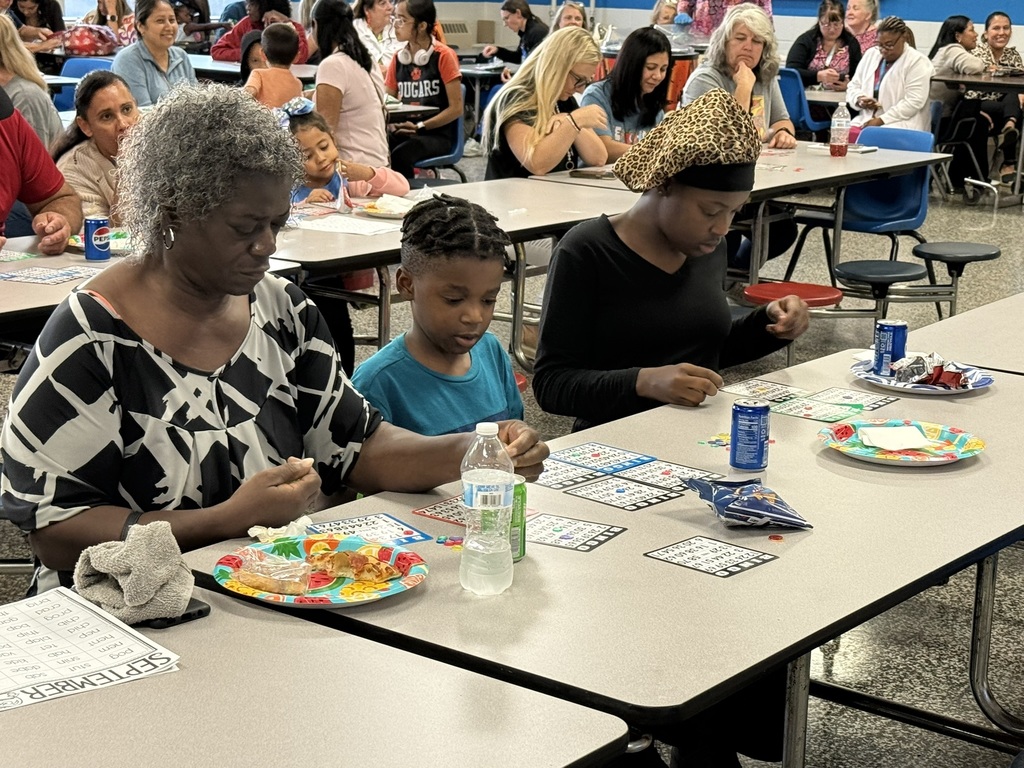 Family sits together concentrating on their Bingo cards while enjoying snacks.
