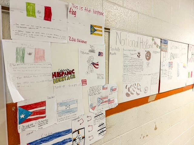 Student-made posters about Hispanic culture and history are displayed on a hallway wall at Elizabethtown Middle School for Hispanic Heritage Month.
