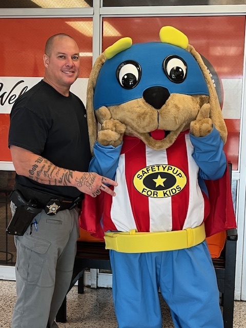 Safety Pup stands with a Bladen County Sheriff’s officer, smiling and posing together for the camera.