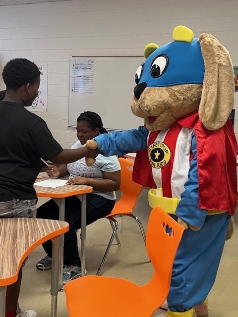 Safety Pup gives a friendly paw shake to a student during a classroom visit at Elizabethtown Middle School.