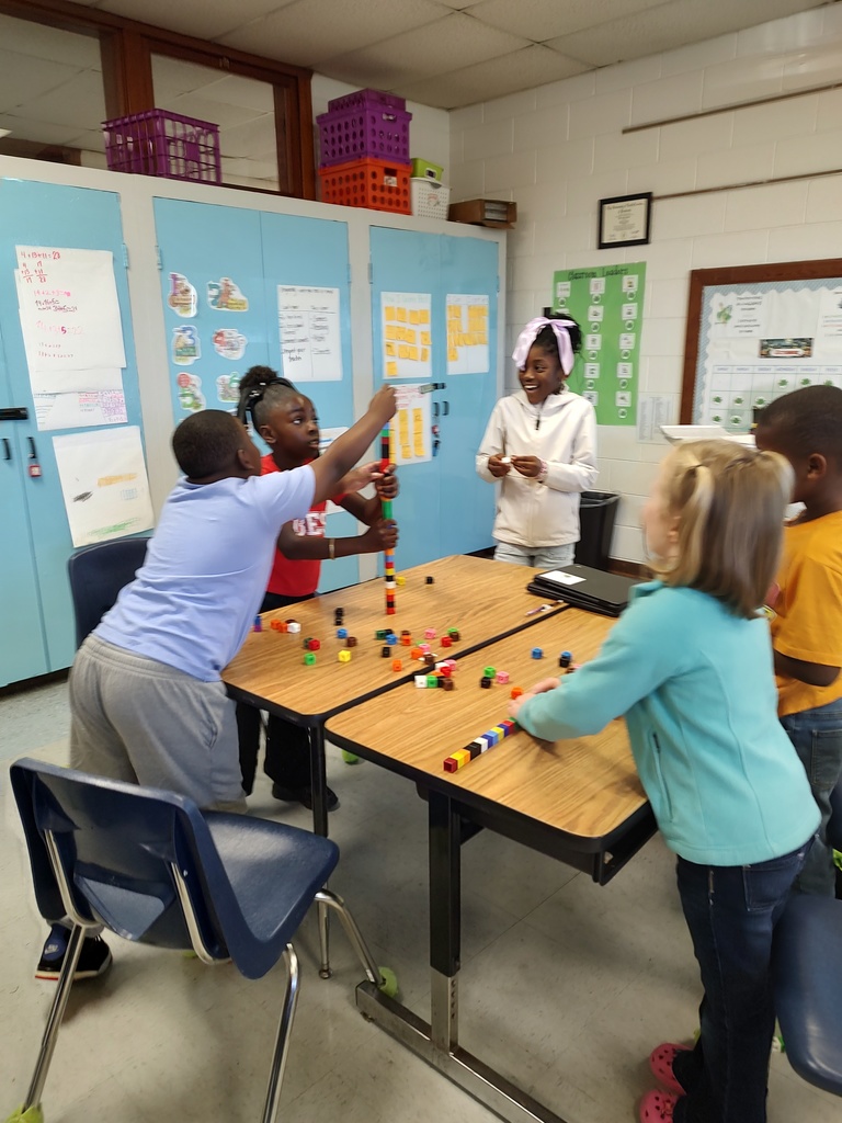 Students work together in small groups using colorful interlocking cubes to build the tallest tower possible.